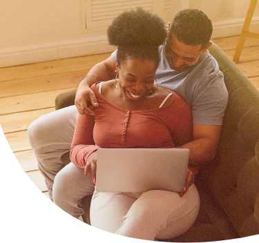 optimistic interracial couple sitting on couch using computer and exploring their options for fertility savings
