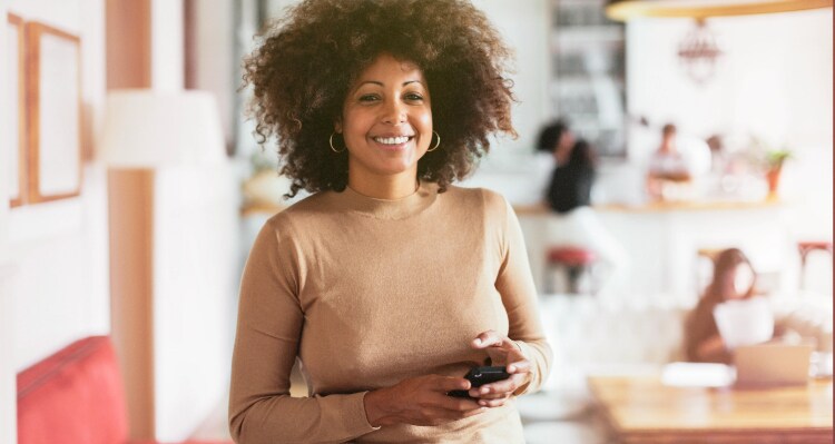 African American woman in her mid 30’s looking at camera holding phone and exploring their options for fertility savings
